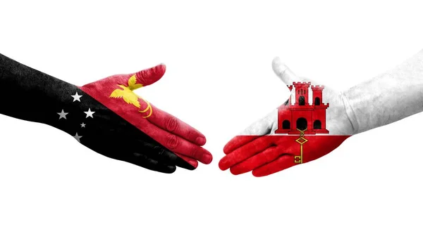 stock image Handshake between Gibraltar and Papua New Guinea flags painted on hands, isolated transparent image.