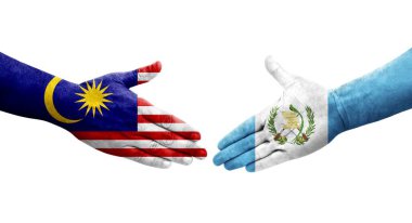 Guatemala ve Malezya bayrakları arasındaki el sıkışma ellerinde izole şeffaf görüntü.