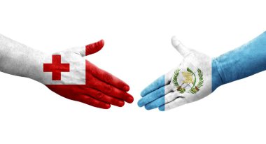 Guatemala ve Tonga bayrakları arasındaki tokalaşma ellerinde izole şeffaf görüntü.