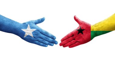 Ellerinde Gine Bissau ve Somali bayrakları arasında el sıkışma, izole şeffaf görüntü.