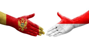 Ellerine boyalı Endonezya ve Karadağ bayrakları arasındaki el sıkışma, izole şeffaf görüntü.