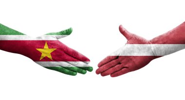 Ellere boyanmış Letonya ve Surinam bayrakları arasındaki el sıkışma, izole edilmiş şeffaf görüntü.