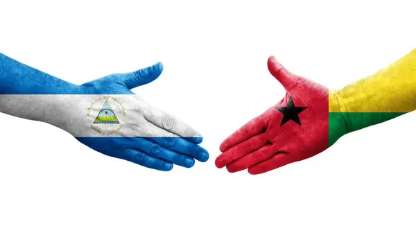 stock image Handshake between Guinea Bissau and Nicaragua flags painted on hands, isolated transparent image.