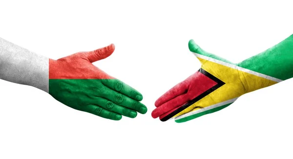 Stretta Mano Tra Guyana Madagascar Bandiere Dipinte Mani Immagine Isolata — Foto Stock