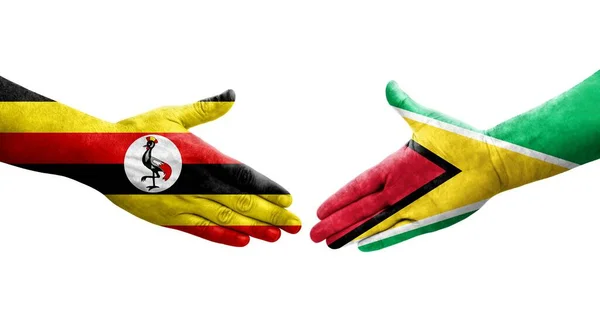 stock image Handshake between Guyana and Uganda flags painted on hands, isolated transparent image.