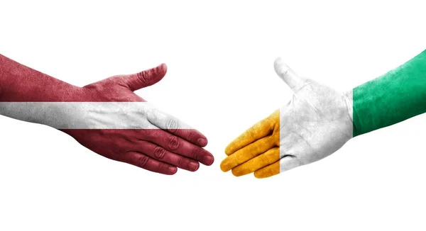 Händedruck Zwischen Der Elfenbeinküste Und Lettland Fahnen Auf Hände Gemalt — Stockfoto