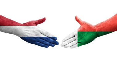 Madagaskar ve Hollanda bayrakları arasındaki tokalaşma elleri boyalı, izole şeffaf görüntü.