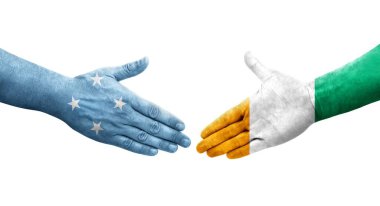 Mikronezya ve Fildişi Sahili bayrakları arasındaki el sıkışma, izole şeffaf görüntü.