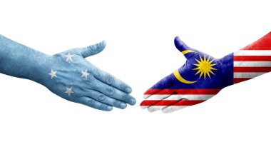 Ellerinde Mikronezya ve Malezya bayrakları arasında el sıkışma, izole saydam görüntü.