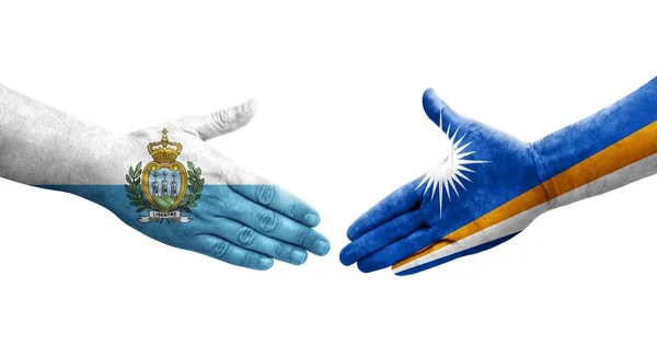 stock image Handshake between Marshall Islands and San Marino flags painted on hands, isolated transparent image.