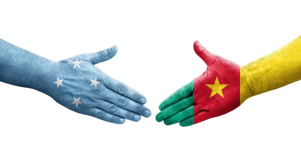 Stock image Handshake between Micronesia and Cameroon flags painted on hands, isolated transparent image.