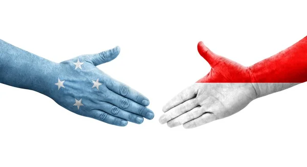 stock image Handshake between Micronesia and Indonesia flags painted on hands, isolated transparent image.