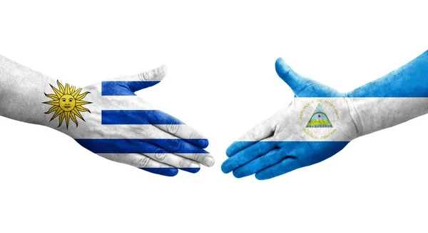 手に描かれたニカラグアとウルグアイの旗の間の握手 孤立した透明なイメージ — ストック写真