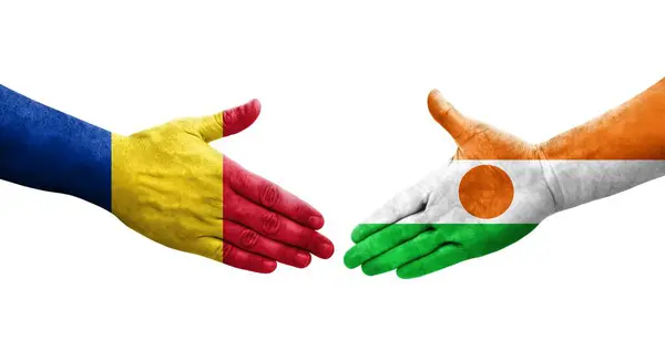 Stock image Handshake between Niger and Romania flags painted on hands, isolated transparent image.