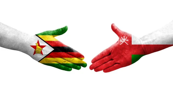 stock image Handshake between Oman and Zimbabwe flags painted on hands, isolated transparent image.