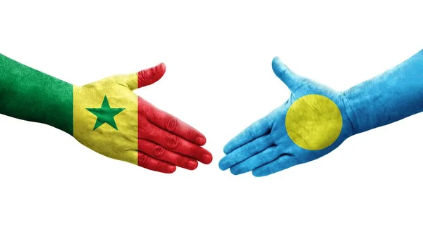 stock image Handshake between Palau and Senegal flags painted on hands, isolated transparent image.