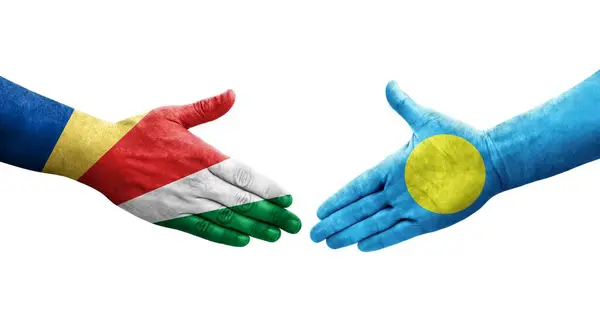 stock image Handshake between Palau and Seychelles flags painted on hands, isolated transparent image.