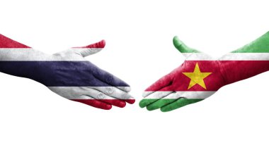 Surinam ve Tayland bayrakları arasındaki el sıkışma ellerinde izole şeffaf görüntü.