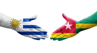 Togo ve Uruguay bayrakları arasındaki tokalaşma elleri boyalı, izole şeffaf görüntü.