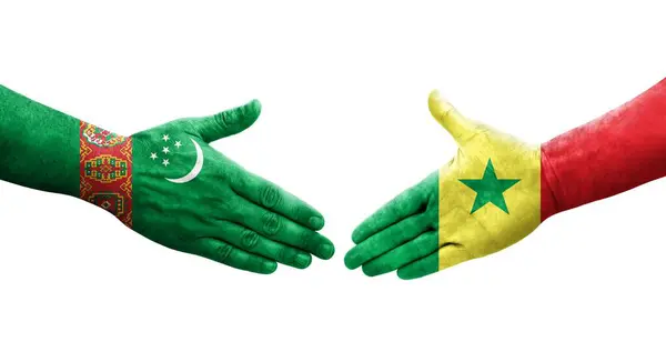 Stock image Handshake between Senegal and Turkmenistan flags painted on hands, isolated transparent image.