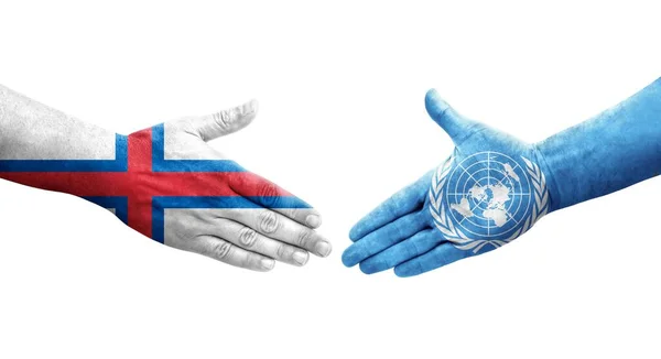 stock image Handshake between United Nations and Faroe Islands flags painted on hands, isolated transparent image.