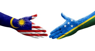 Solomon Adaları ve Malezya bayrakları arasındaki el sıkışma ellerinde izole şeffaf görüntü.