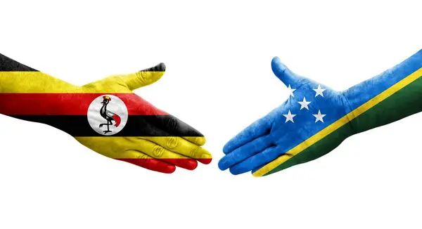 stock image Handshake between Solomon Islands and Uganda flags painted on hands, isolated transparent image.