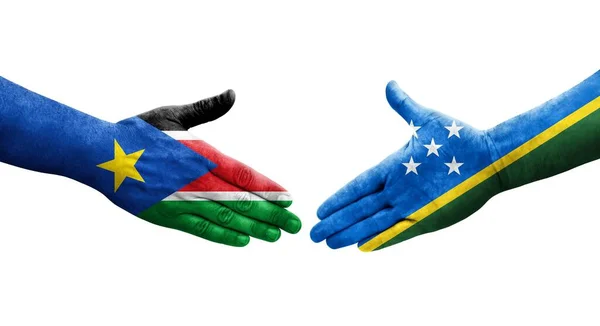 stock image Handshake between Solomon Islands and South Sudan flags painted on hands, isolated transparent image.