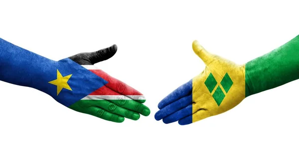 stock image Handshake between Saint Vincent Grenadines and South Sudan flags painted on hands, isolated transparent image.