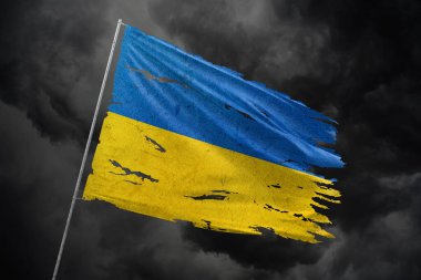 Karanlık gökyüzü arka planında Ukrayna 'nın yırtık bayrağı.