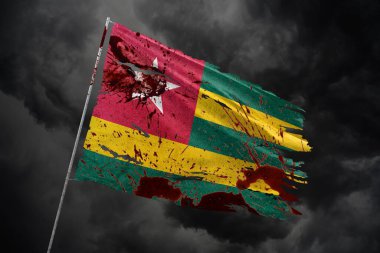 Togo kan lekeleriyle gökyüzü arka planında parçalanmış bayrak.