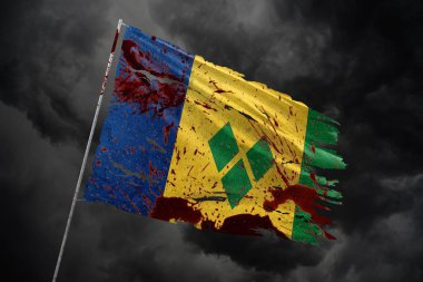 Aziz Vincent Grenadines 'in kan lekeleriyle dolu koyu gökyüzü arka planında yırtık bayrakları.