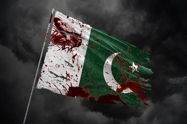 Pakistan 'ın kan lekeleriyle dolu karanlık gökyüzü arka planında yırtık bir bayrak.