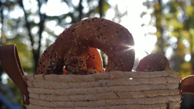 Gün batımında hasır bir sepette sağlıklı organik susamlı simit. Fırınlanmış malların arasından güneş ışınları