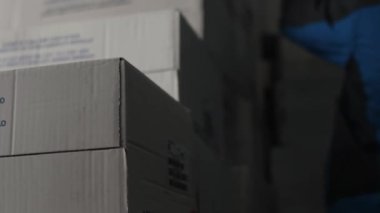 Tanınmayan işçiler depoya karton kutular, siparişler, alımlar, e-ticaret ürünleri yükler.