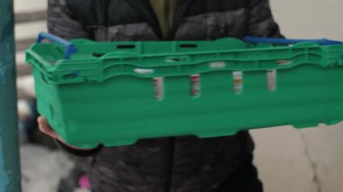 Bir kamyondan mülteciler için bağışlanan yiyeceklerin olduğu plastik kutuyu boşalt. Tanımlanamayan erkek eller gönüllü zinciri bir market kutusunu elden ele gezdiriyor.