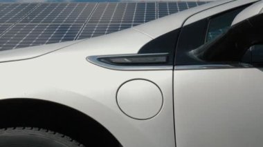 Erkek el, arka plandaki EV veya elektrikli arabayı şarj etmek için güç kablosu desteğini bağlar. Fotovoltaik şarj istasyonunda bir elektrikli otomobil ya da PHEV takan tanınmayan bir adam