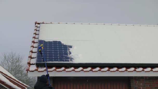 雪から太陽電池パネルを掃除する 冬にソーラーパネルで電気を供給する 冬季の太陽エネルギーパネル 太陽電池パネルから雪を晴らす認識できない男 冬季の再生可能エネルギーについて — ストック動画
