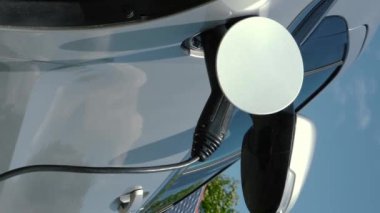 Fotovoltaik şarj istasyonunda tanımlanamayan adamın dikey videosu. Erkek eller, arka plandaki güneş panellerine EV veya elektrikli araba yüklemek için güç kablosu desteğini keserler