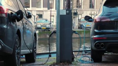 Kentsel elektrikli araçlara güç veriliyor, PHEV çevre dostu enerji çözümlerinden faydalanıyor. EV kanalın yakınındaki bir sokak istasyonunda şarj oluyor, sürdürülebilir şehir ulaşımını gösteriyor