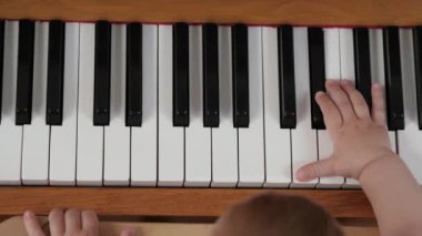 Bebek parmaklar piyano tuşlarına basar. Küçük çocuk piyano çalıp müzik öğrenmeye çalışıyor. Çocuk müzisyenin eli piyano çalmayı öğreniyor, müzik aleti, yakın plan.