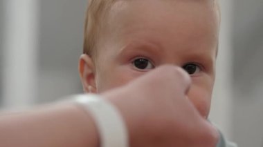 Bebek pis bir suratla yer ve kameraya bakar, kapat. Bebek ağzını açar ve taze meyve, elma, armut, şeftali yer. Anne eli küçük oğlunu besler.