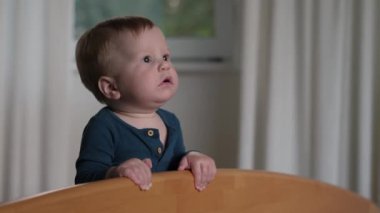 Bebek bebek kendine güvenle ayakta duruyor ve merakla etrafına bakıyor, merak ve neşeli keşfin özünü mükemmel bir şekilde yakalıyor, sıcak, rahat bir ortamda.