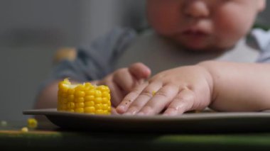 Neşeli bebek, çocukluğunun keyifli ve maceralı ilk yıllarında kendini beslemenin getirdiği saf mutluluğu gösteren koçandaki parlak, altın mısırı mutlulukla keşfeder.