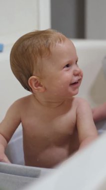 Neşeli bebeğin dikey videosu küvette mutlu bir şekilde oynuyor. Masumiyeti ve keyifli, kahkahalarla dolu o güzel banyo anlarının güzel ruhunu yakalıyor.