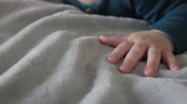 Yumuşak ve pelüş bir battaniyeye uzanmış, saf masumiyet ve neşeyi sembolize eden gerçekten değerli ve hassas bir anı yakalayan, minik bebek ellerinin yakın çekimi.