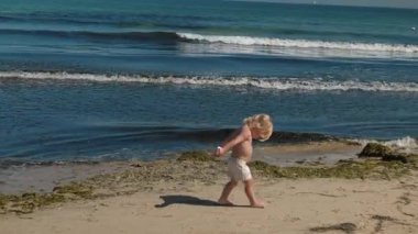 Güzel sıcak bir günde, kaygısız çocuk sevinçle kıyıları keşfeder, nazik dalgaların yanında mutlu bir şekilde oynar, doğanın sersemletici güzellikleri arasında saf çocukluk masumiyetini yakalar.