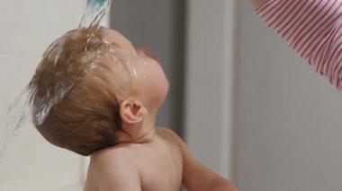 Mutlu bebeğin saçı banyoda yıkanır. Bu da masumiyeti ve neşe ve kahkahalarla dolu o güzel banyo anlarını mükemmel bir şekilde yakalar.