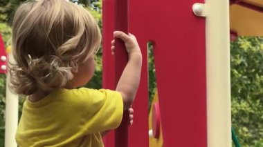 Canlı sarı bir tişörtle giyinmiş neşeli küçük bir çocuk neşeli ve neşeli bir oyun alanını keşfediyor, doğal meraklarını ve doğanın güzelliğindeki saf oyunlarını sergiliyor.