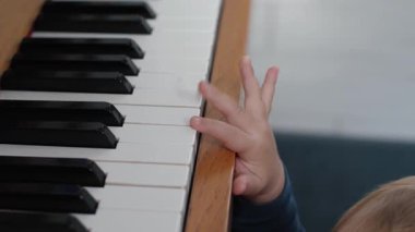 Çocuk müzisyenlerin elleri piyano çalmayı öğreniyor, müzik aleti, yakın plan. Bebek piyano çalmaya çalışıyor, müzik öğreniyor. Küçük çocuk parmakları piyano tuşlarına basar